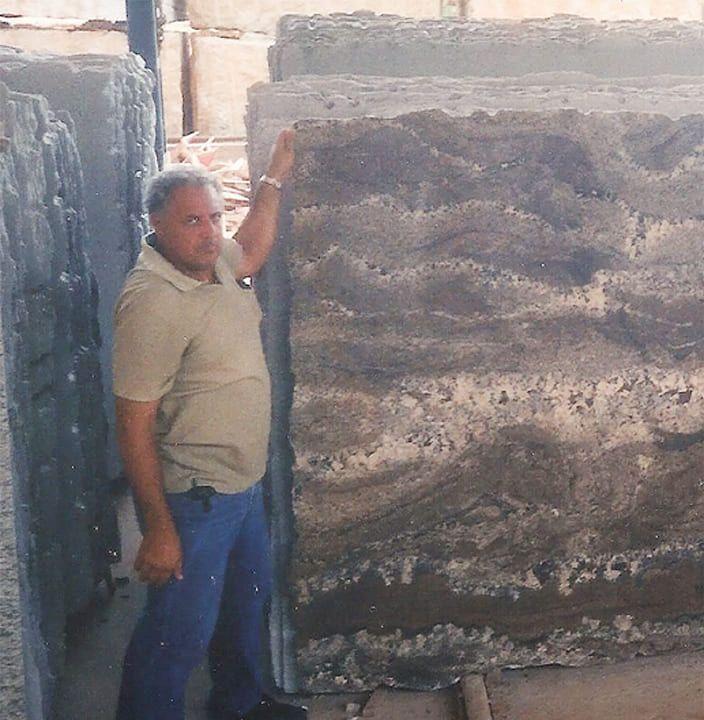 Fundador da Sabagram ao lado de grandes chapas de rocha natural, no início da operação.